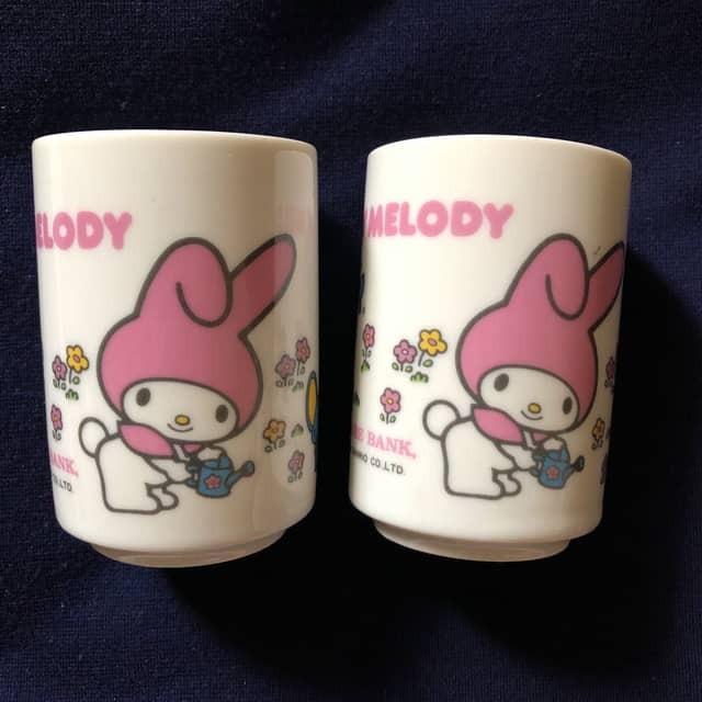 Deux tasses à thé japonaises en céramique blanche, décorées de My Melody à la capuche rose arrosant des fleurs.