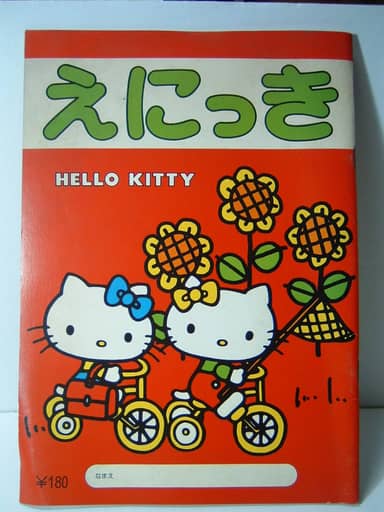 Couverture orange d'un cahier « えにっき » où deux Hello Kitty font du vélo au milieu de tournesols.