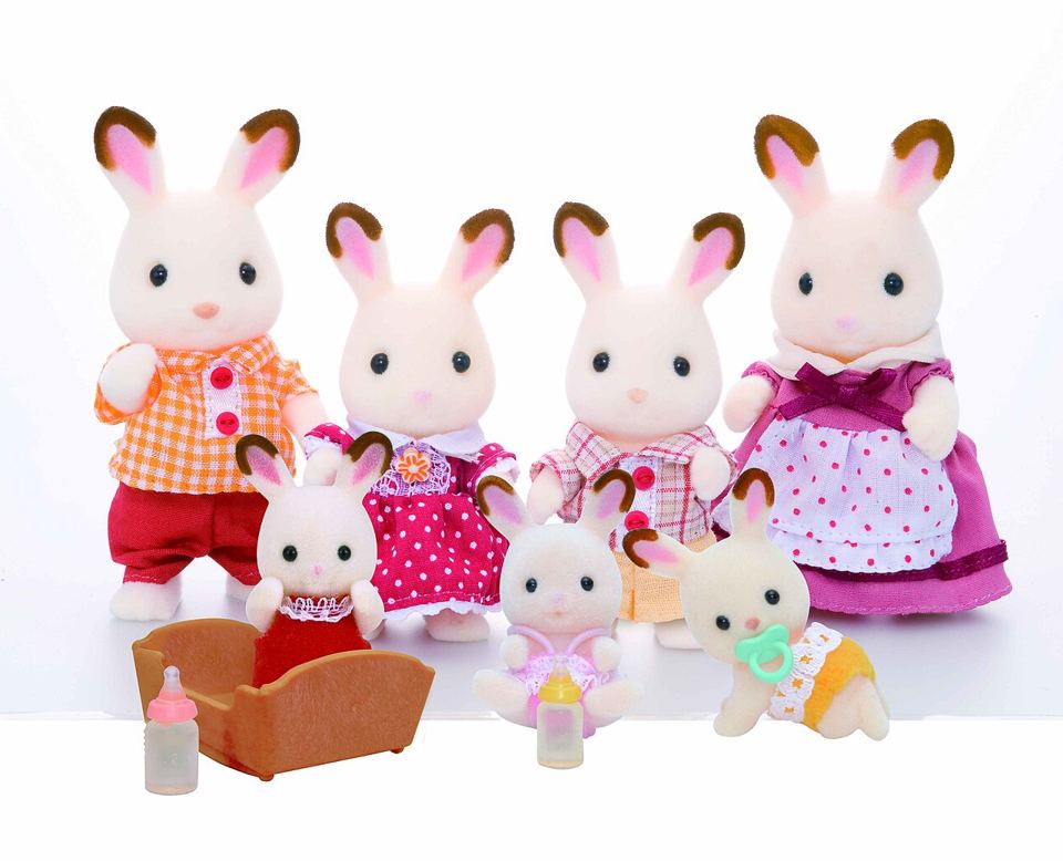 Famille de lapins Sylvanian au pelage crème et aux oreilles brunes : parents, deux enfants et trois bébés avec un berceau et des biberons.